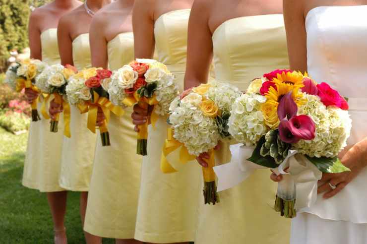 women wears white and yellow tube strapless dresses holding white red and yellow bouquet